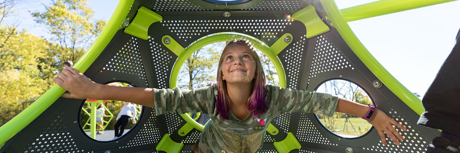 A girl plays inside a playground climbing cube.